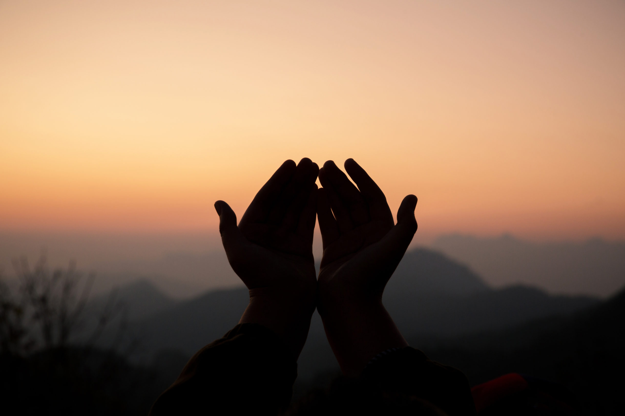 Person praying outside at sunrise